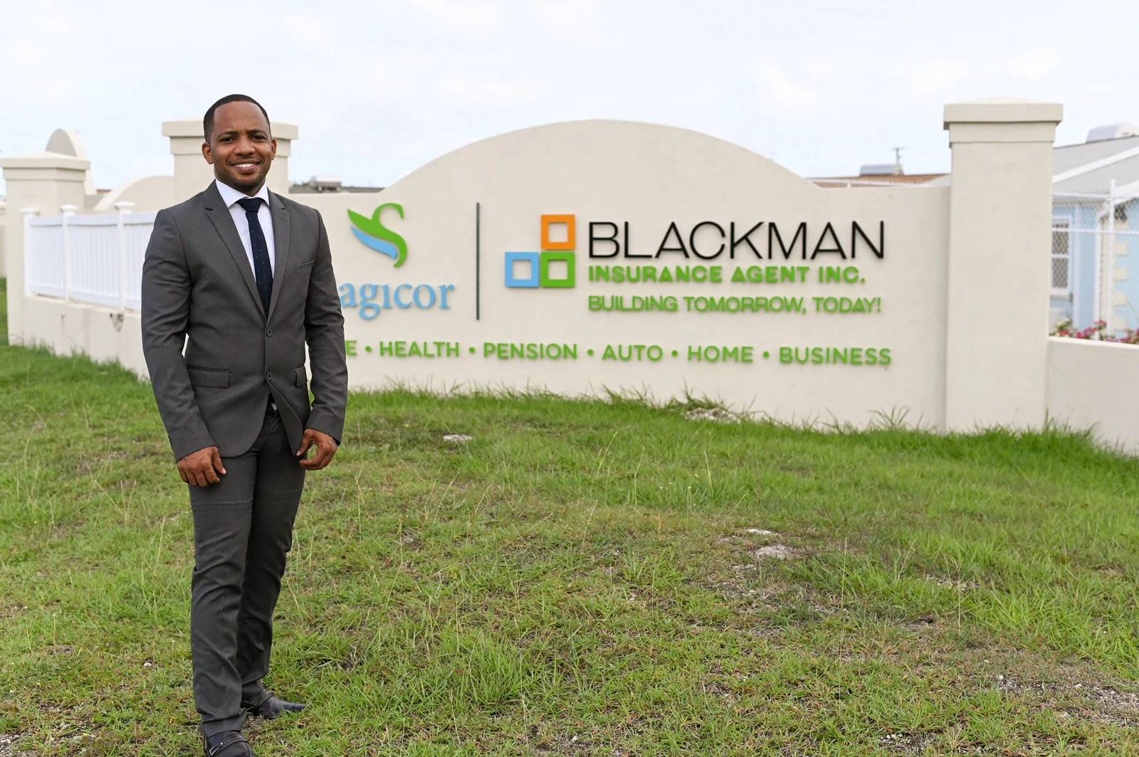 Jamar Blackman beside the Blackman Insurance Agent Inc. and Sagicor sign