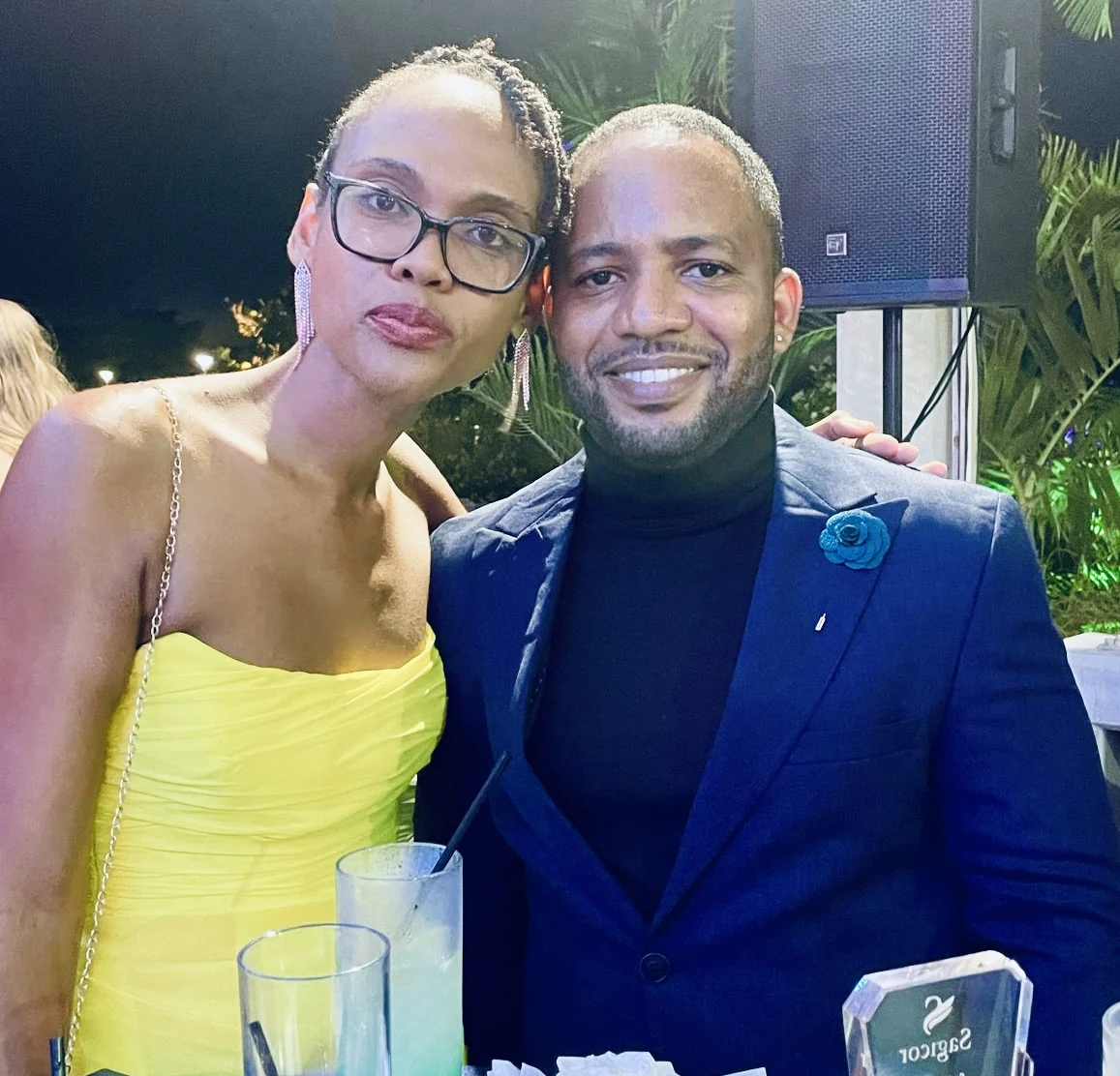 Jamar and a woman in a yellow dress at an evening gathering