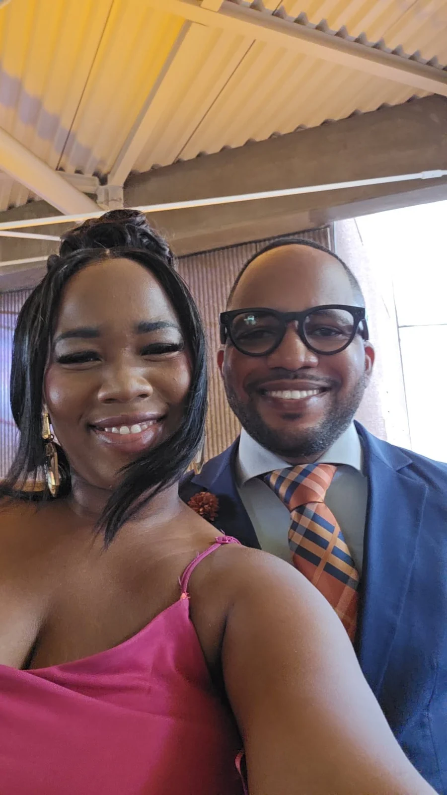 Jamar wearing glasses beside a woman in pink