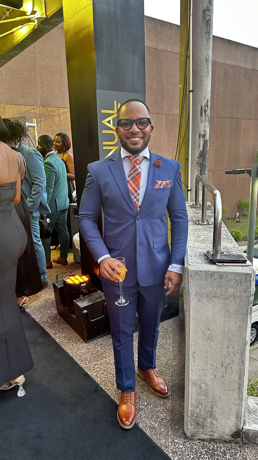 Jamar in a blue suit and orange tie at a venue entrance