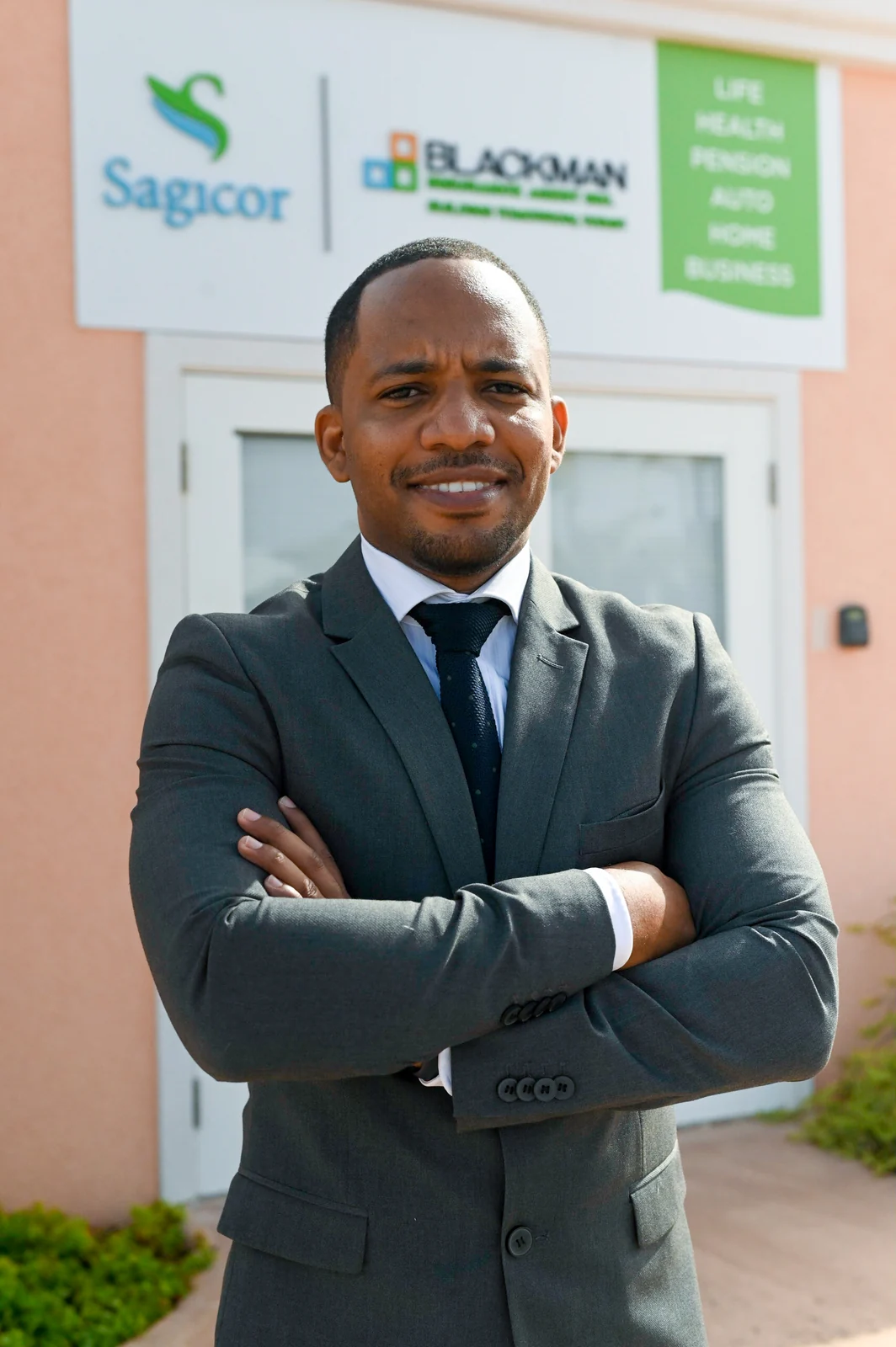 Jamar Blackman outside BIAI, with the agency and Sagicor signage behind him